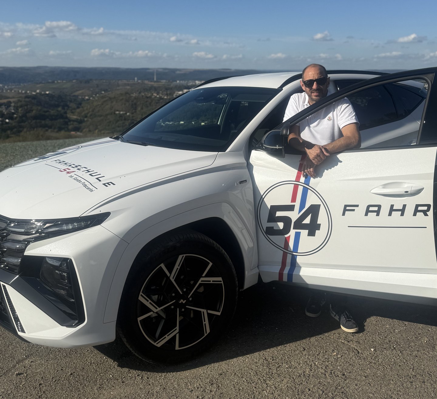 Sandro Foscarini, Inhaber der Fahrschule 54, an der geöffneten Tür seines Fahrschulautos